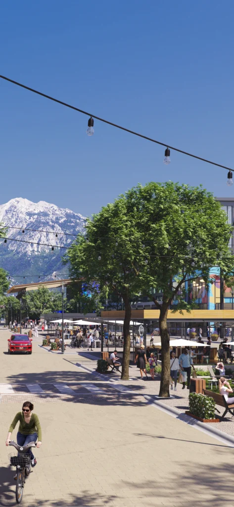 A lively pedestrian-friendly urban district set against a stunning mountain backdrop. The image showcases a bustling street lined with modern buildings featuring retail shops, cafes, and restaurants. People are walking, shopping, and dining outdoors, while others cycle or relax on benches under tree-lined sidewalks. Overhead string lights add charm to the atmosphere, and a sleek architectural design blends with the natural surroundings. In the distance, snow-capped mountains rise majestically, enhancing the sense of harmony between urban life and nature.