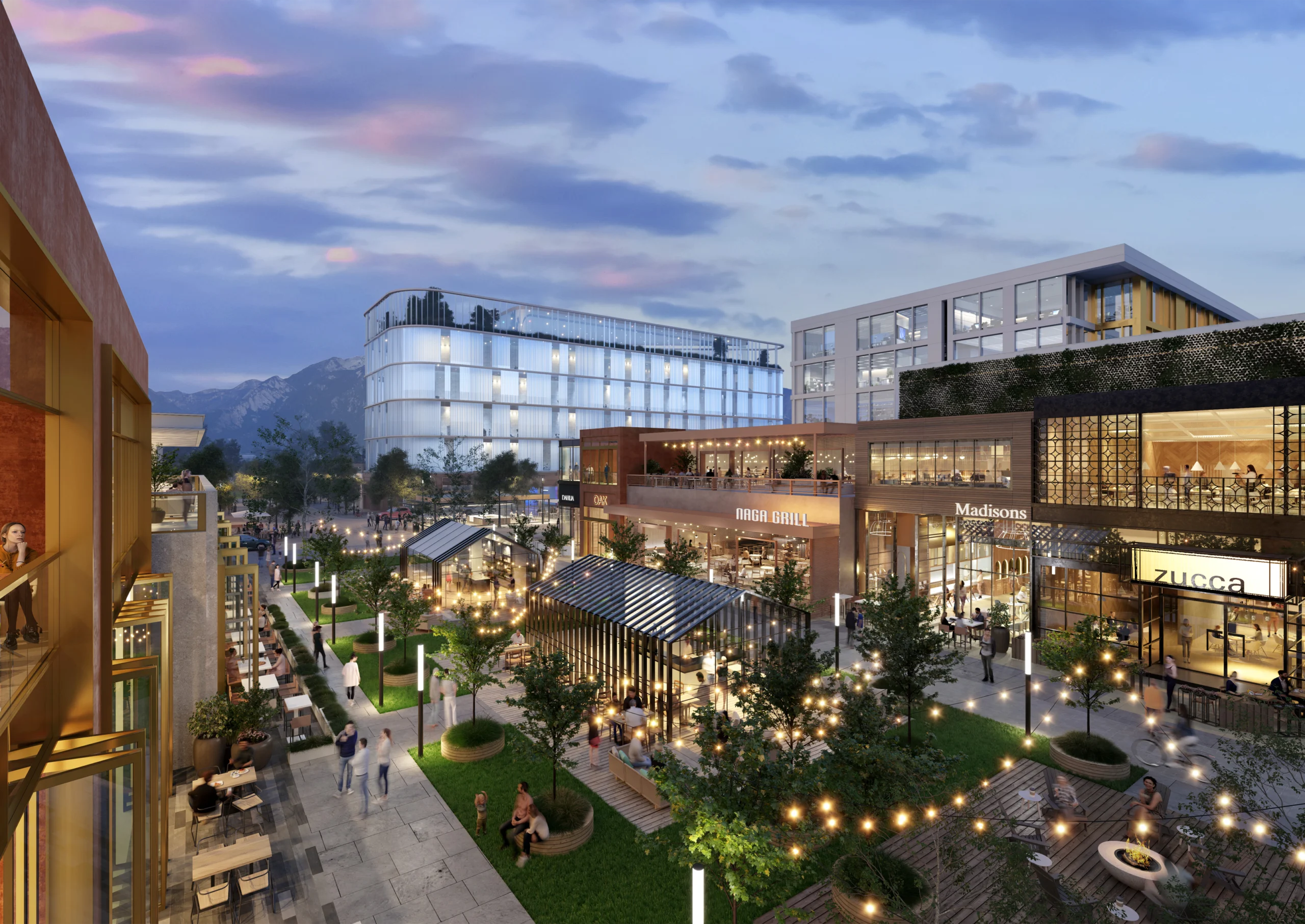 A vibrant urban courtyard featuring a modern mixed-use development. The scene includes illuminated pathways lined with trees, outdoor seating areas, and decorative lights. Contemporary buildings surround the area, displaying visible signs such as "Naga Grill," "Madisons," and "Zucca." In the background, a sleek glass office building stands against distant mountains under a pastel evening sky. People are seen walking, dining, and enjoying the lively atmosphere.